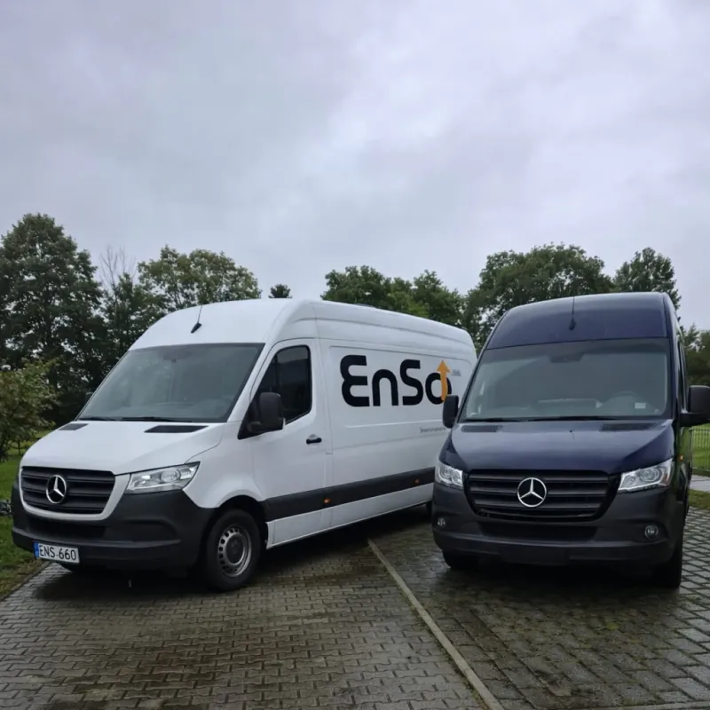 Zwei Mercedes-Benz Sprinter Transporter, nebeneinander auf einer nassen asphaltierten Fläche geparkt, einer weiß mit „EnSa”-Logo und einer dunkelblau.